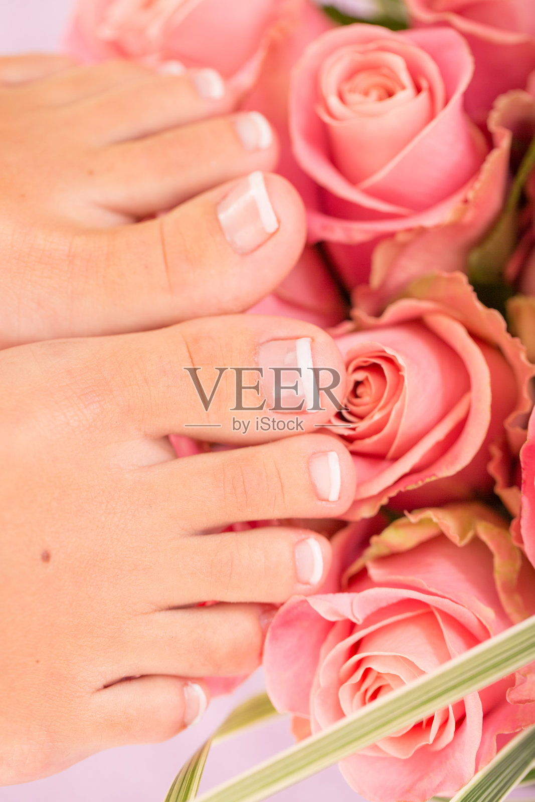 女人在粉红色玫瑰花上修脚后的脚照片摄影图片