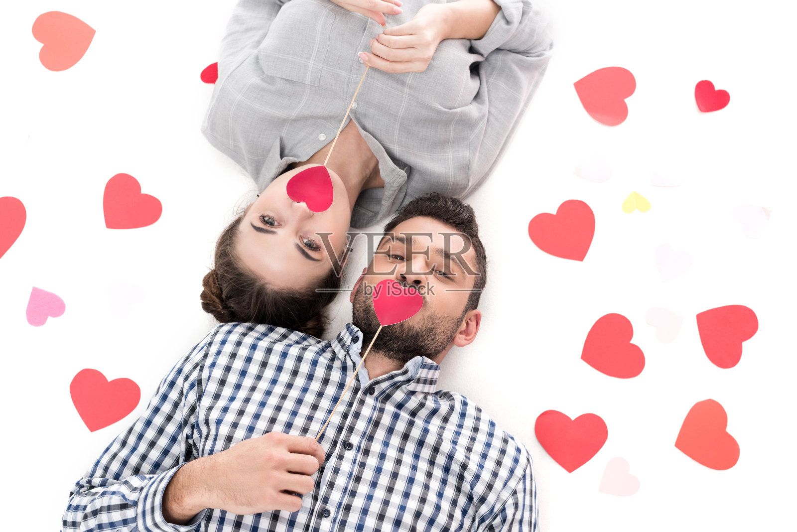 头顶上的情侣躺在纸上，心与白色隔离，情人节的概念照片摄影图片