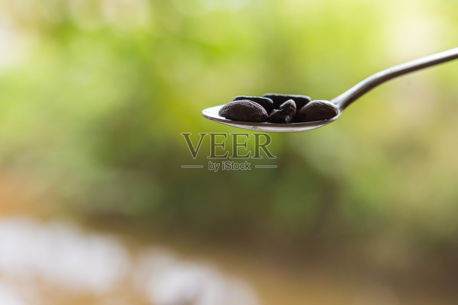 勺子里的咖啡豆，背景模糊不清照片摄影图片