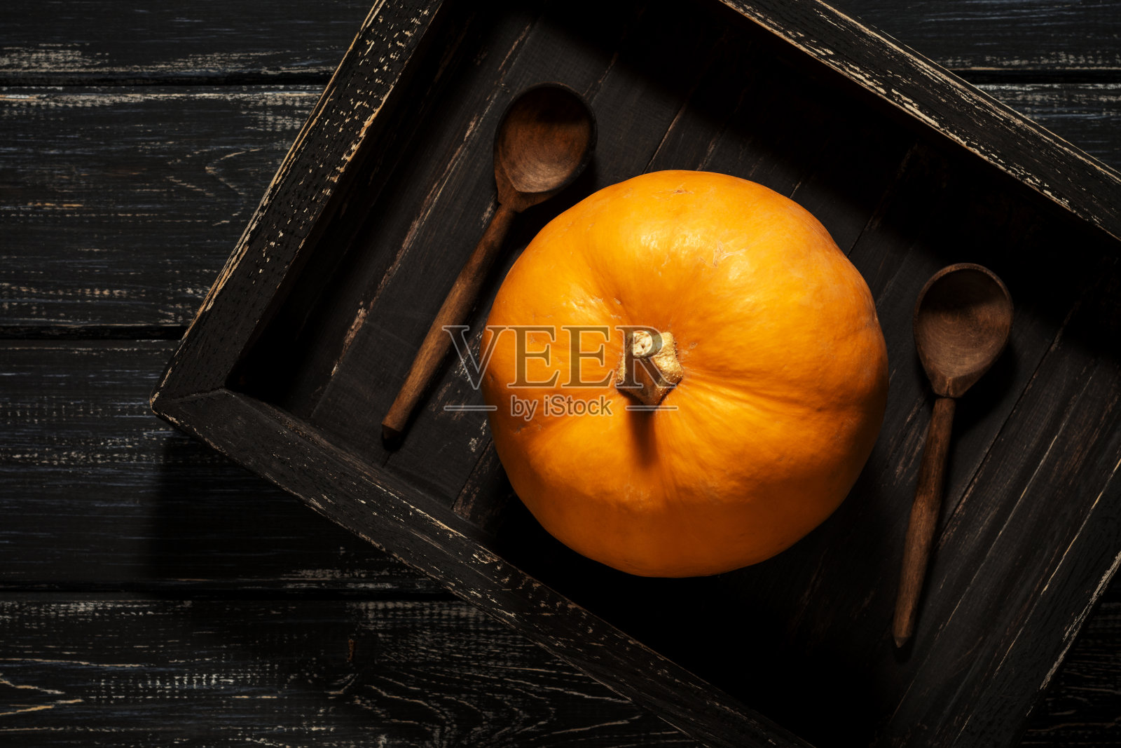 一个小南瓜放在一个黑色的木托盘和木勺子的乡村风格。从以上观点。照片摄影图片