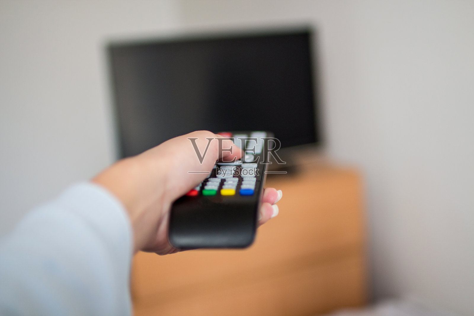 用电视遥控器的女人。照片摄影图片