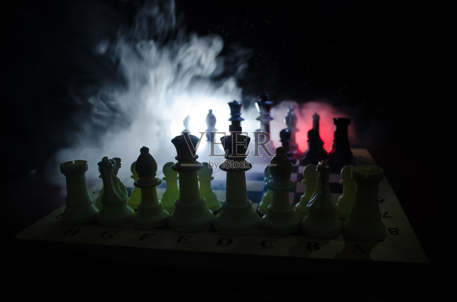 棋牌游戏的经营理念和竞争理念以及战略理念。象棋人物在烟雾缭绕的黑暗背景上。照片摄影图片