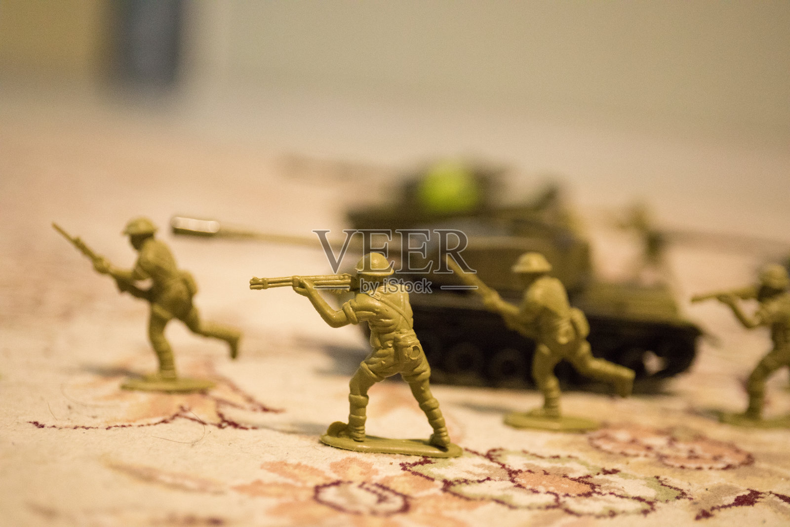 微型玩具士兵和坦克在船上。战争中的玩具军队的特写。照片摄影图片