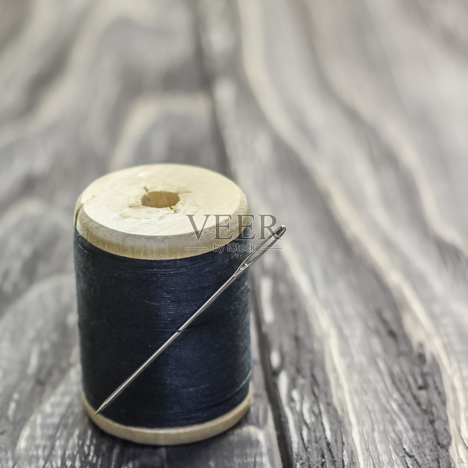 在一个散发着恶臭的黑色木头上，特写镜头，一个带针的线轮。照片摄影图片