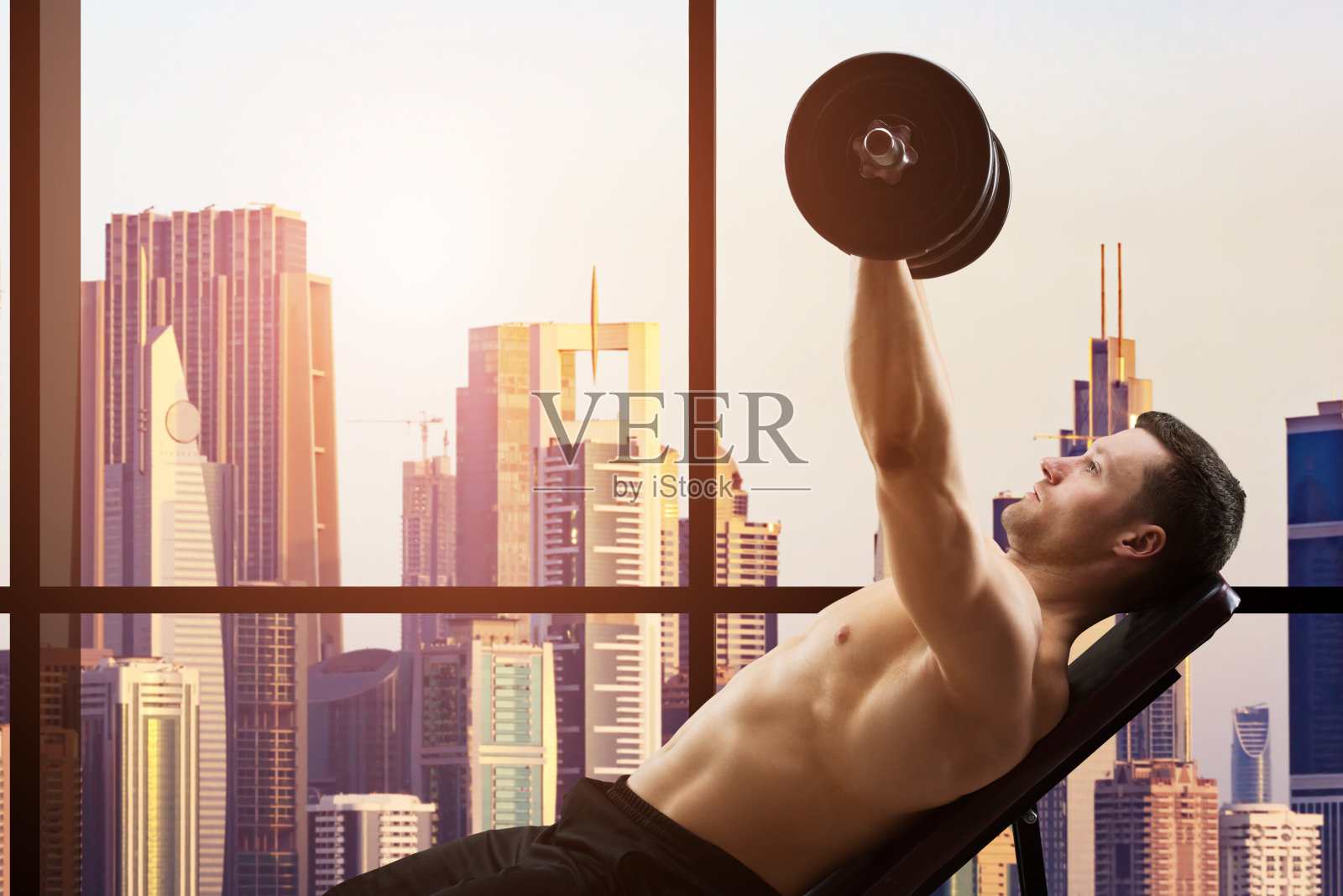 躺在椅子上举哑铃的坚定男人照片摄影图片