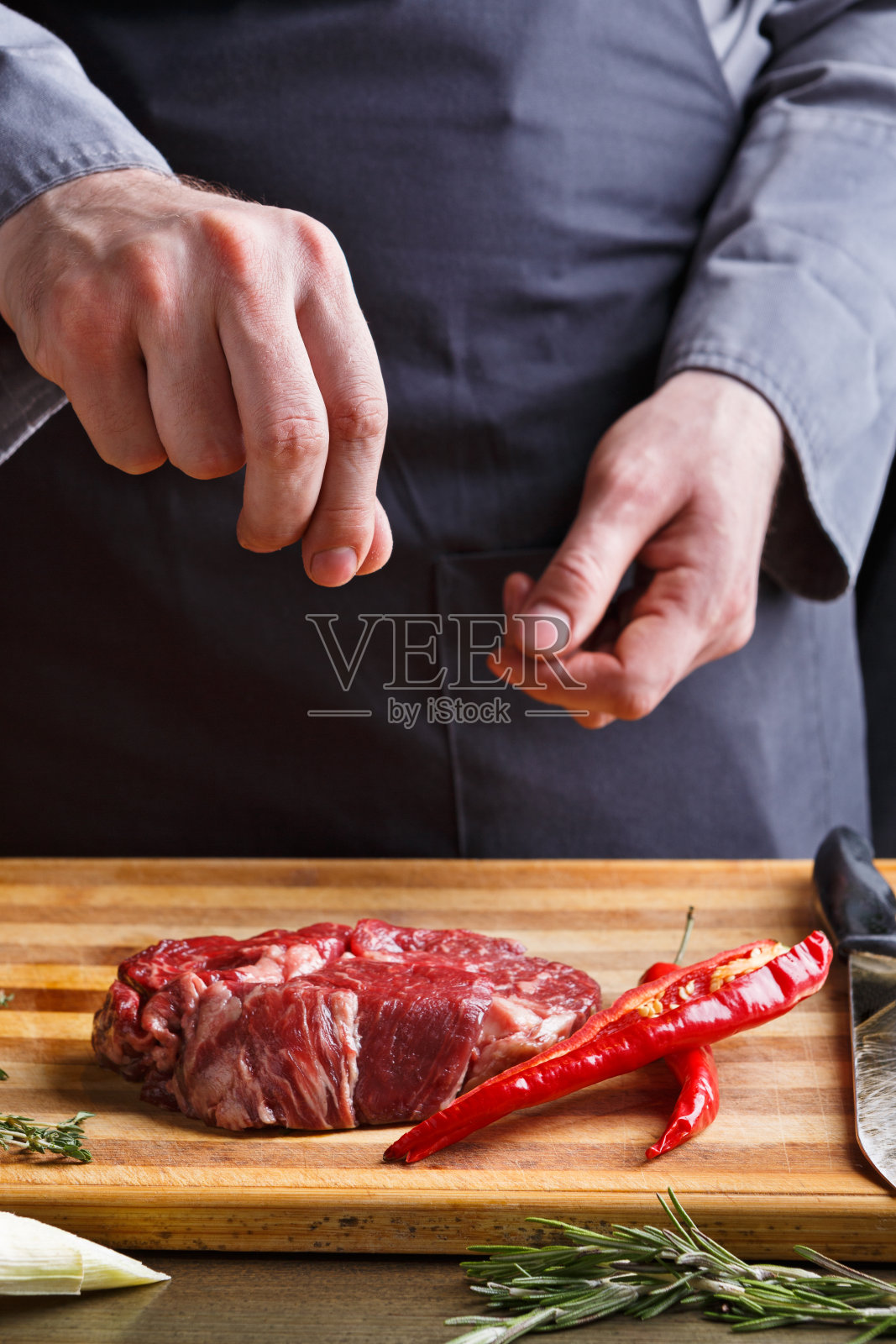 厨师在餐厅厨房的木板上为肋眼牛排调味照片摄影图片