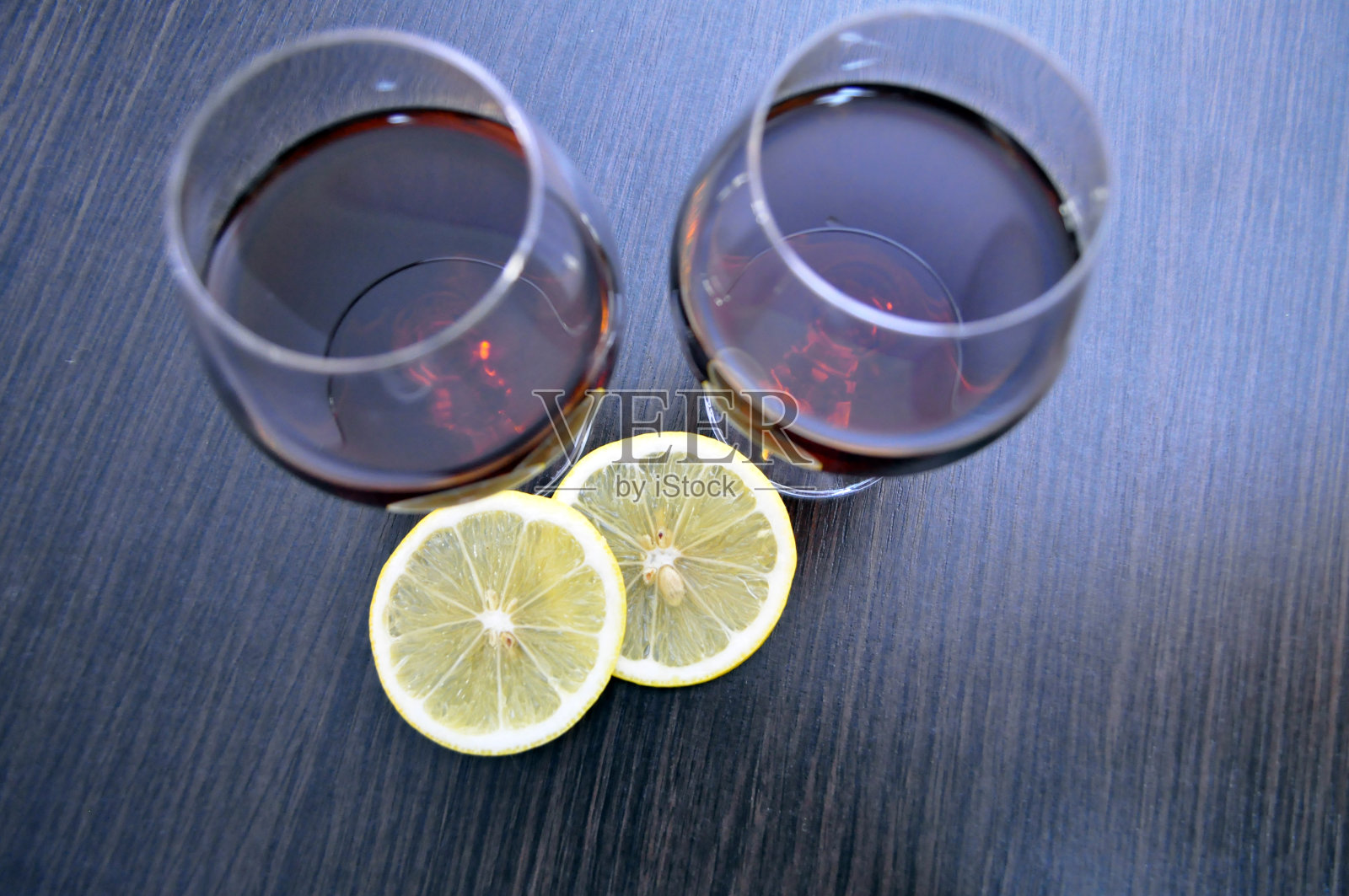 两杯白兰地加柠檬和一支燃烧的蜡烛照片摄影图片