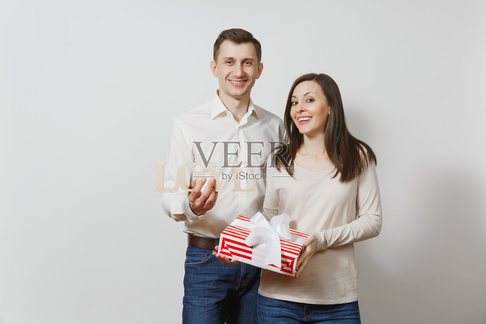 可爱的情侣在相爱。男人，女人用木字写着爱，礼物盒用白色背景孤立着礼物。为广告。情人节、国际妇女节、生日、节日概念。照片摄影图片