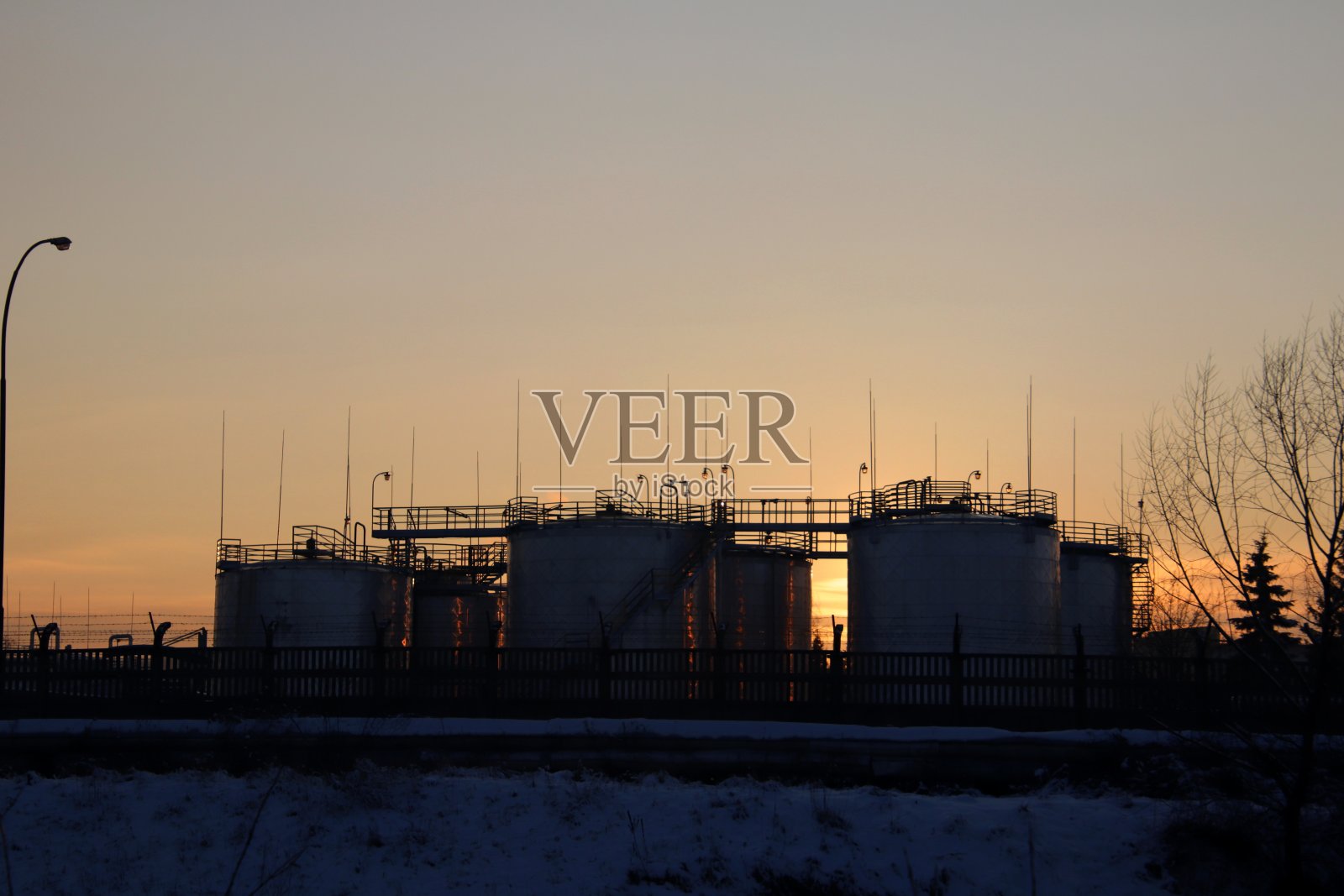 在日落中剪影与储罐的炼油厂。照片摄影图片