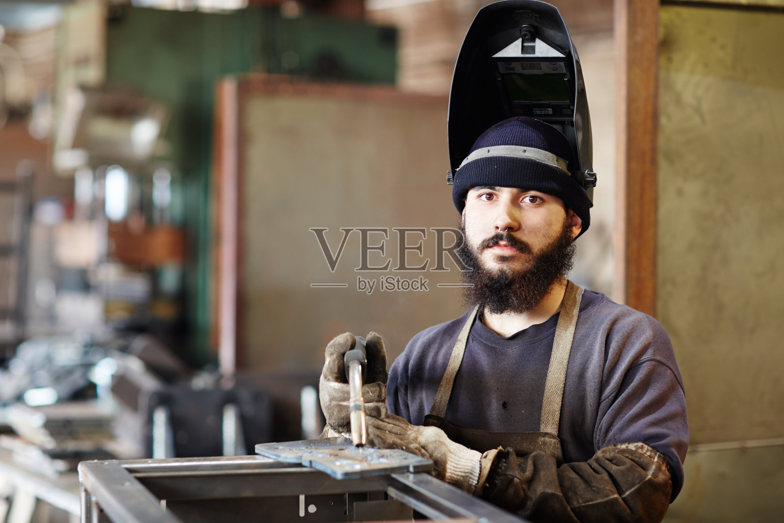 戴着头盔，满脸胡须的焊工照片摄影图片