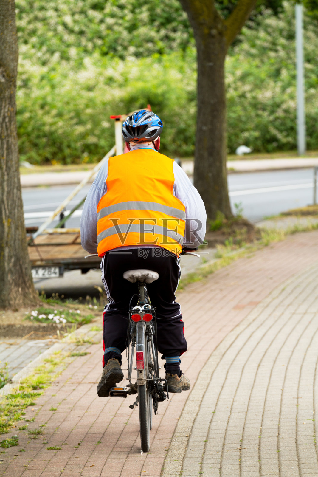 骑自行车戴头盔和橙色反光背心的老年人照片摄影图片