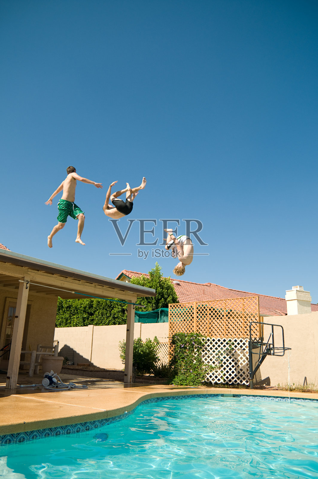 三个年轻人从屋顶跳进游泳池照片摄影图片