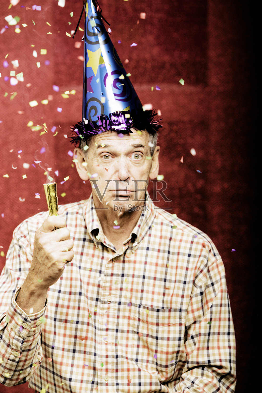 戴着派对帽，上面撒着五彩纸屑的老人照片摄影图片