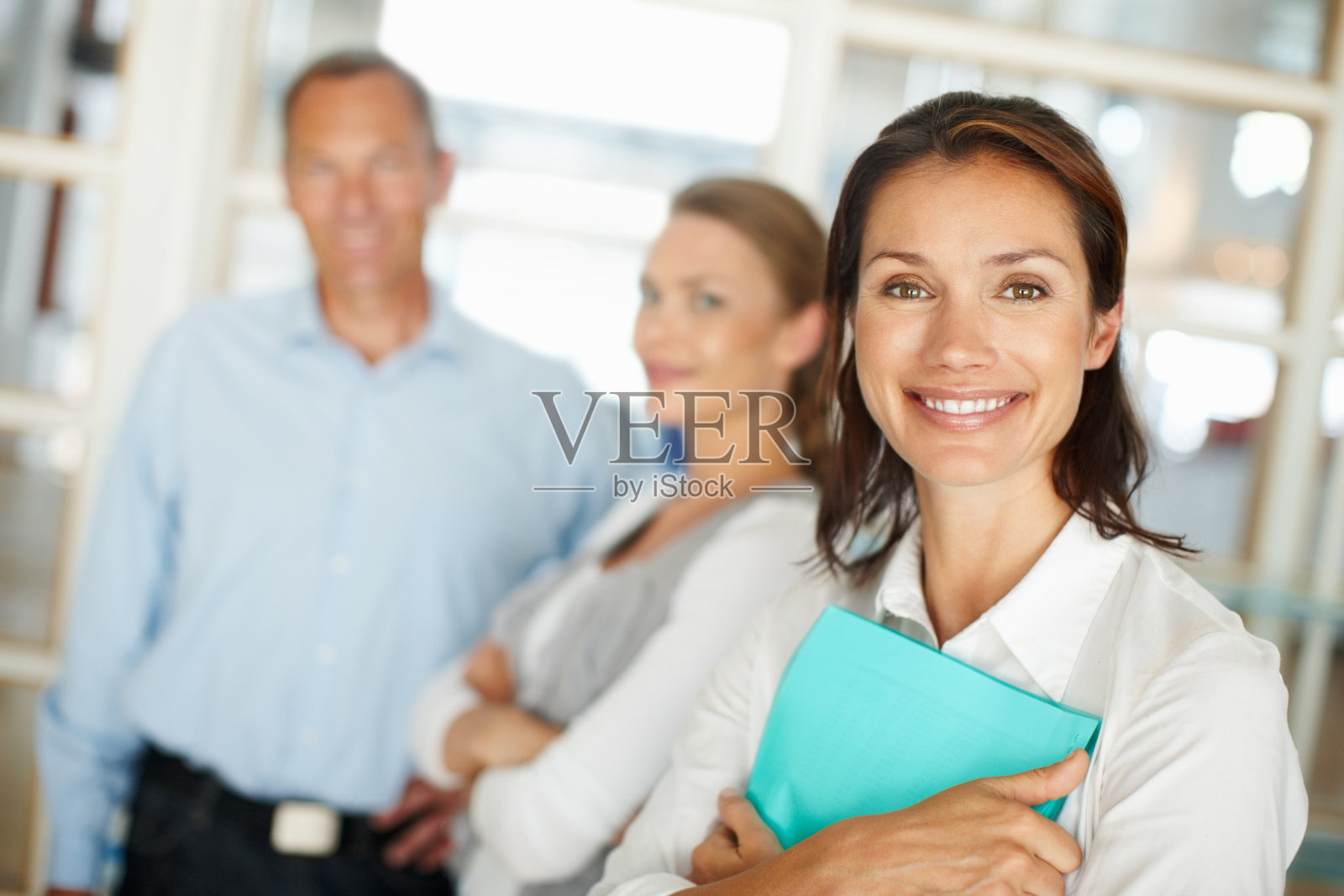 快乐的女商人拿着文件夹和同事在后台照片摄影图片