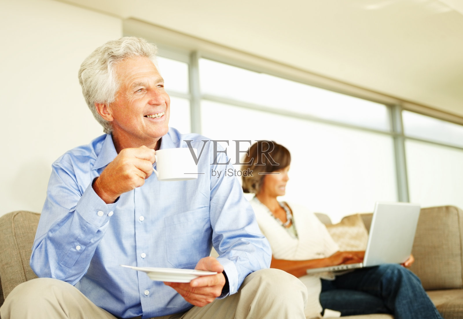 成熟的男人喜欢喝一杯咖啡，女人在他身后工作照片摄影图片