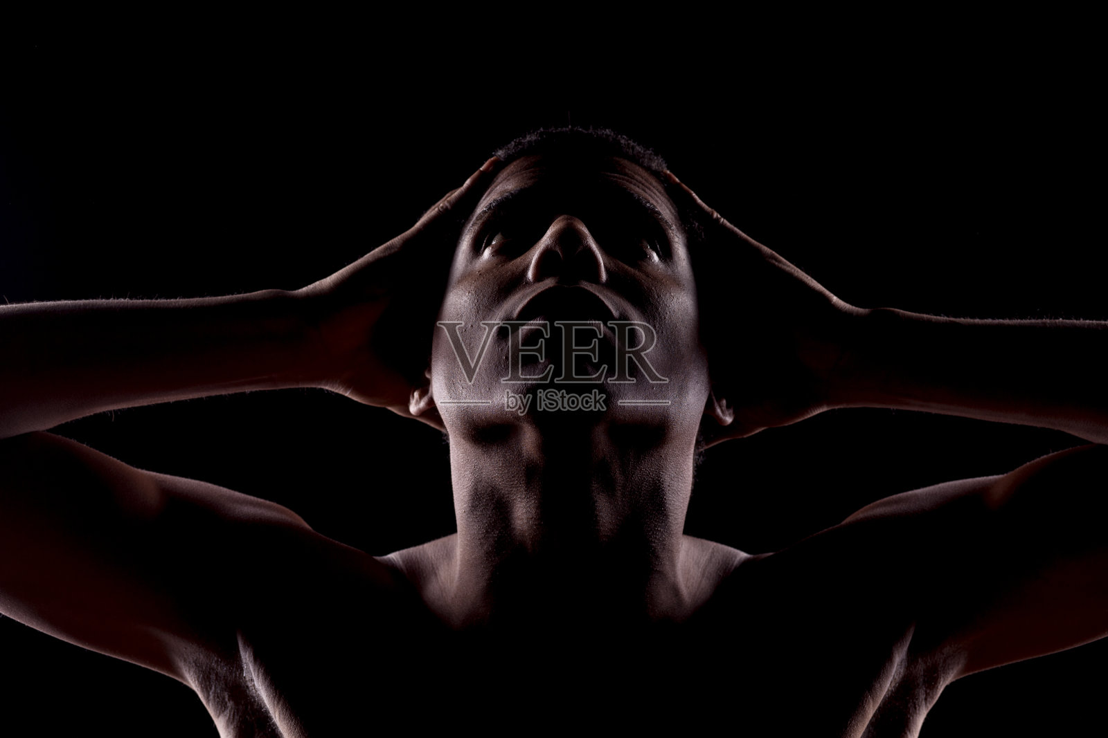 一个无名男子，她的脸在阴影中向上看照片摄影图片