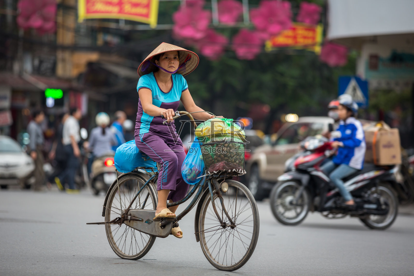 在越南河内的交通中骑自行车的女人照片摄影图片
