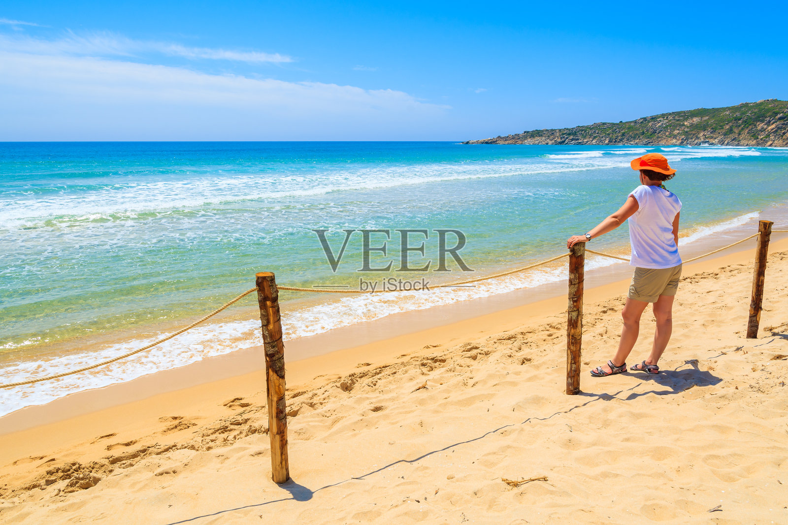 一名年轻女子站在意大利撒丁岛奇亚海滩的篱笆旁照片摄影图片