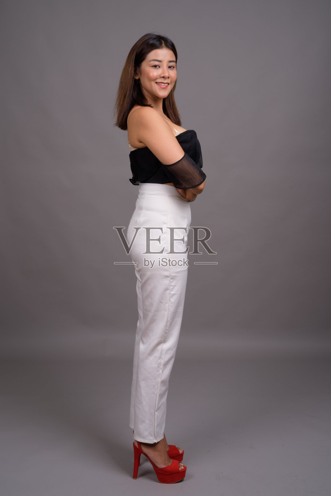 工作室拍摄的年轻美丽的亚洲女人穿掉了肩上的灰色背景照片摄影图片