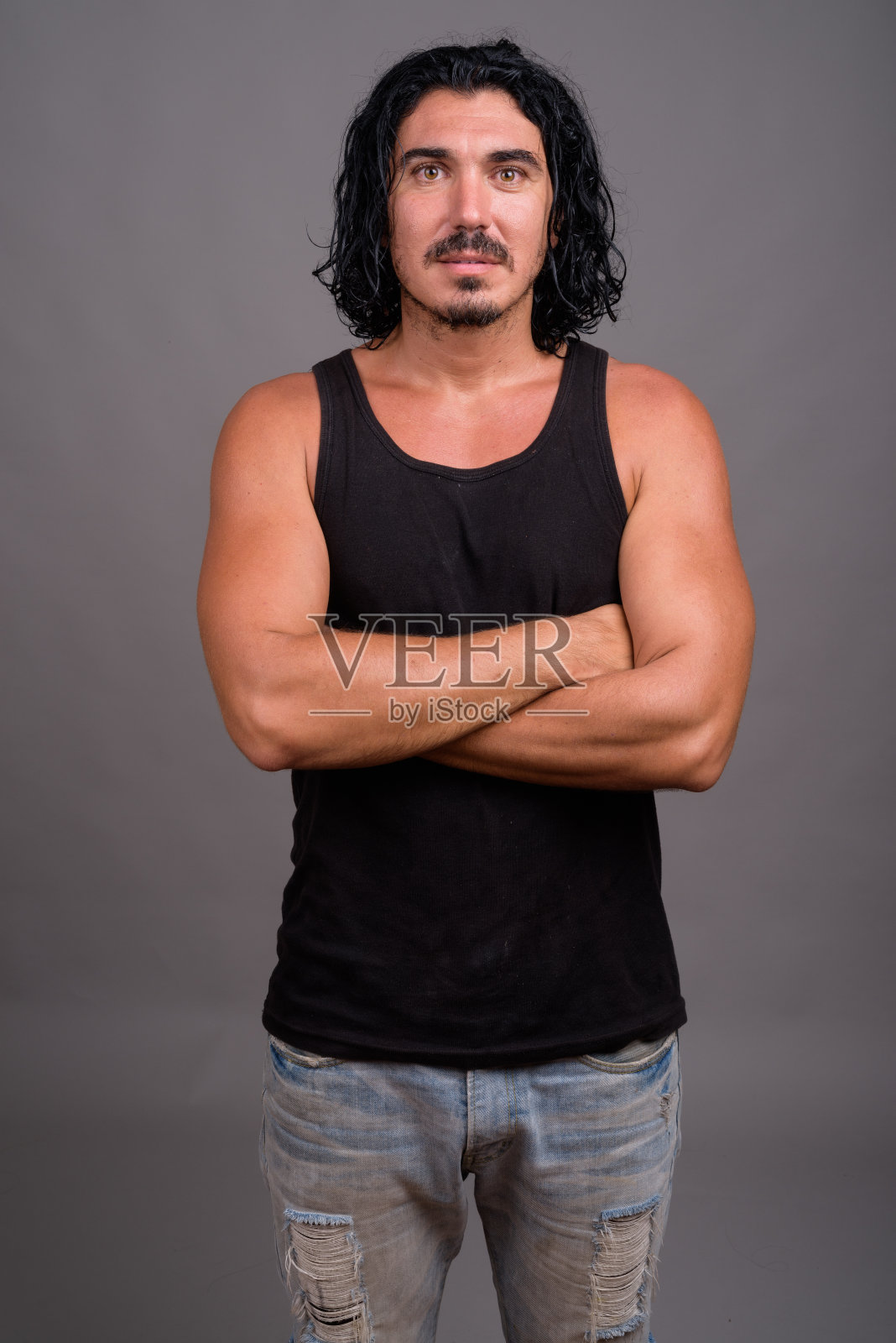 工作室拍摄的年轻英俊的男子与胡子穿背心对灰色背景照片摄影图片