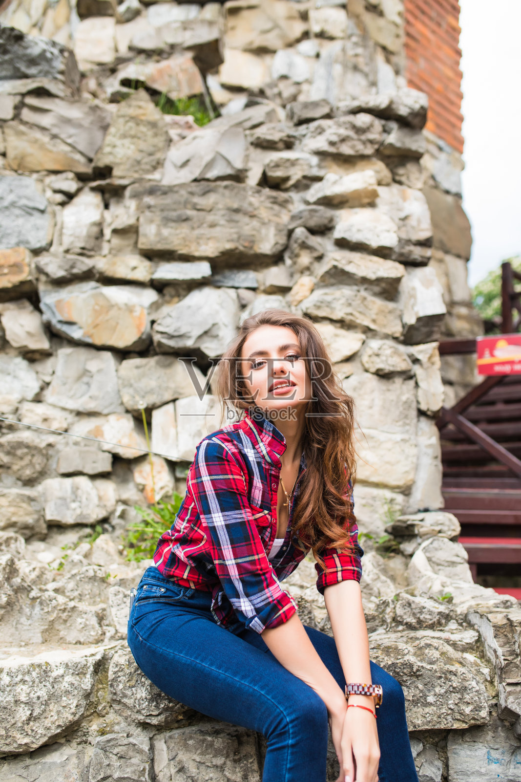 漂亮的年轻苗条的女人靠在石墙上摆姿势照片摄影图片