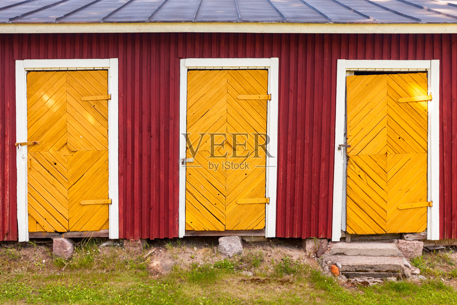 红色农村谷仓里的三扇黄色上锁的门照片摄影图片