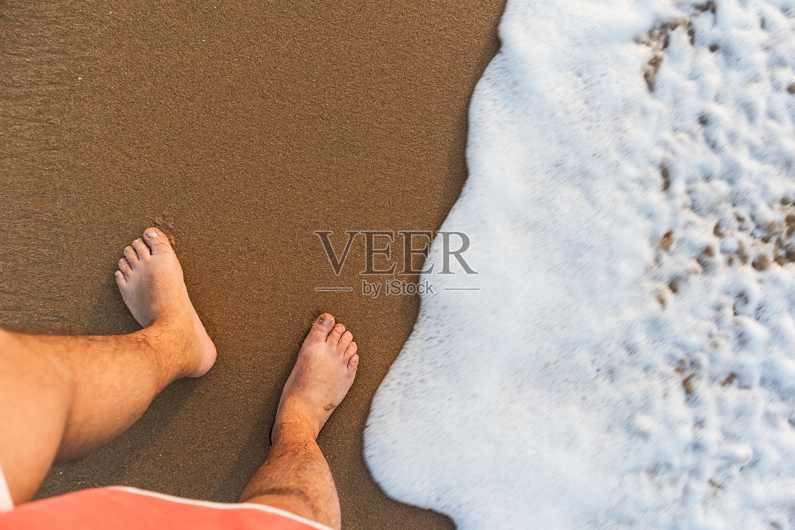 从上面看人的脚和海水。照片摄影图片