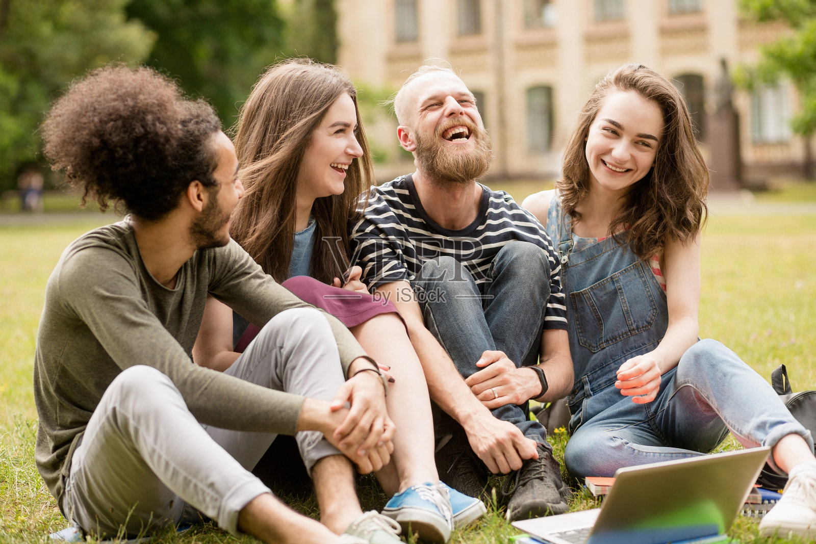 学生们在大学公园的草地上快乐地笑着。照片摄影图片