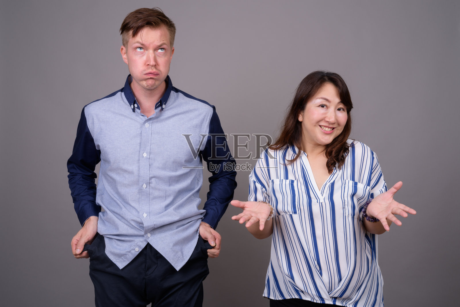 工作室拍摄的年轻英俊的商人和成熟的亚洲女商人在灰色的背景照片摄影图片