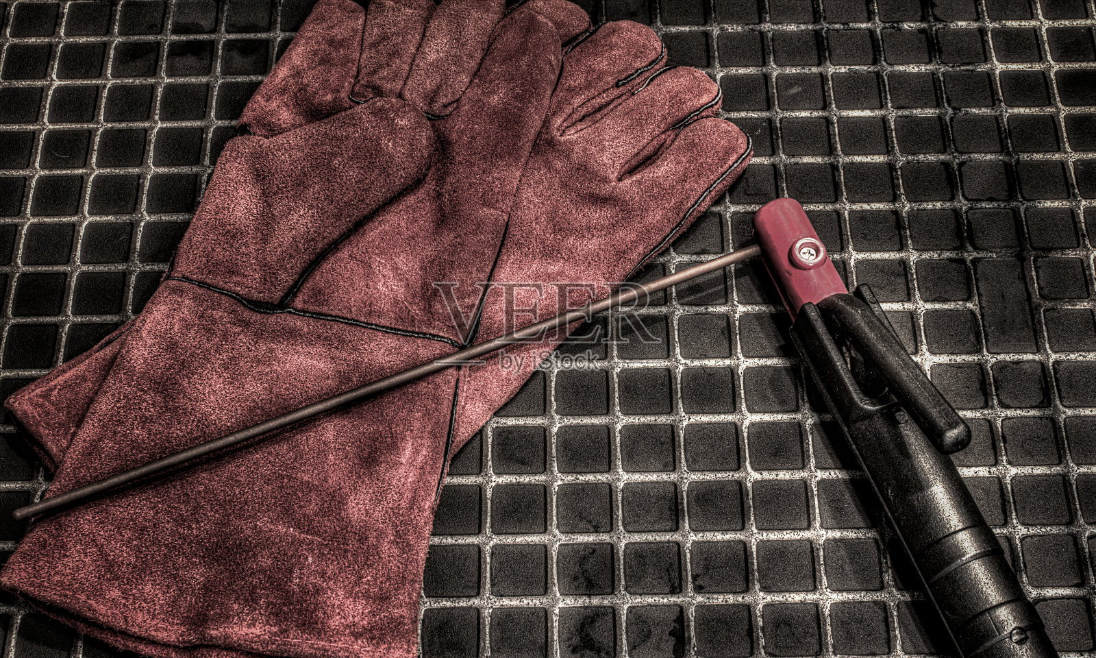 对焊工手套。橙色皮革手套和焊条。焊机的配件。照片摄影图片