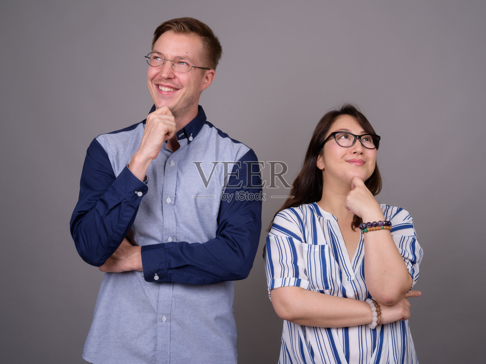 工作室拍摄的年轻英俊的商人和成熟的亚洲女商人在灰色的背景照片摄影图片