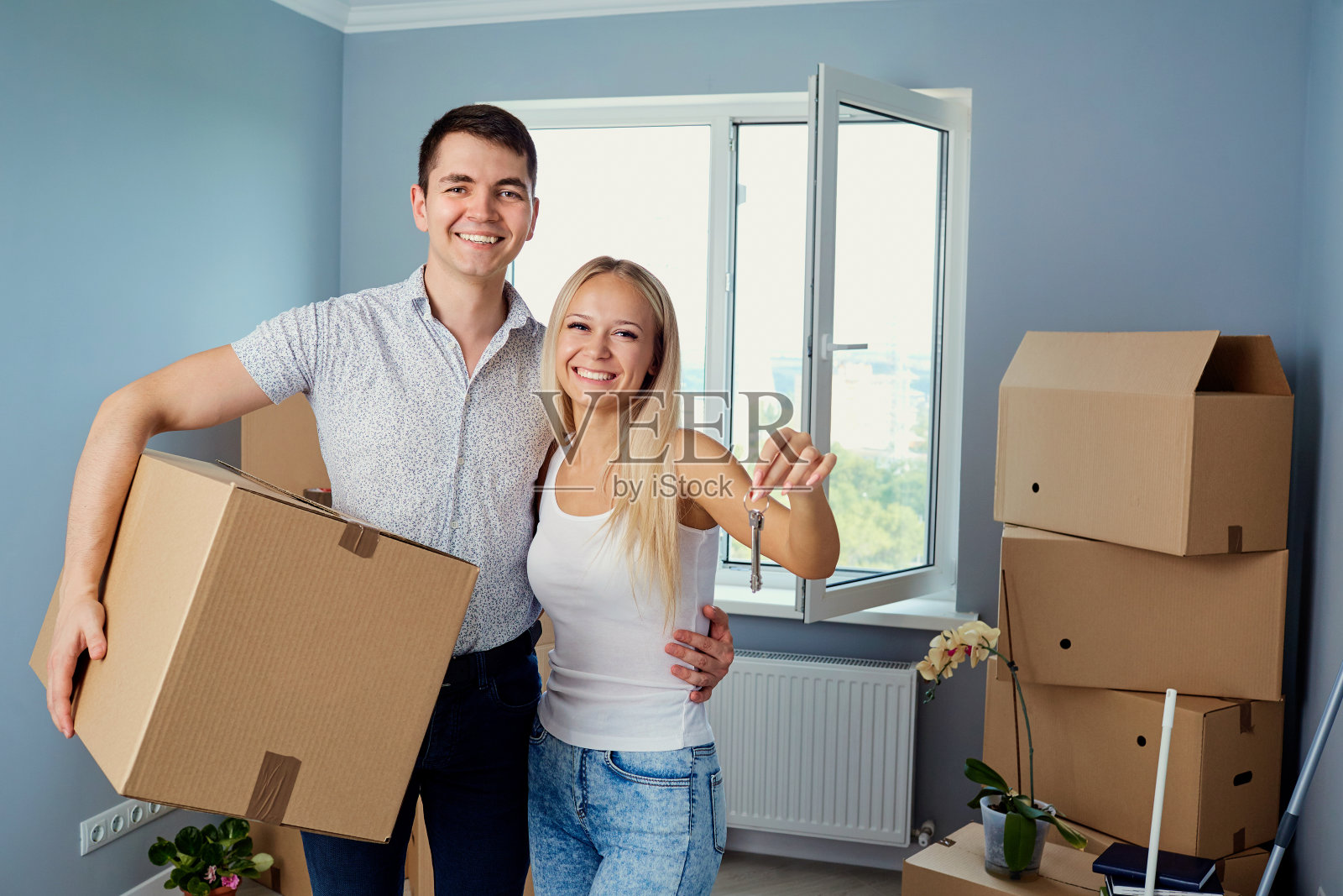 一对年轻夫妇带着钥匙进入新房。照片摄影图片