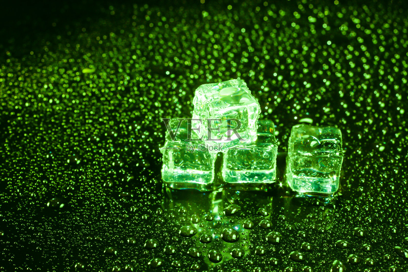 绿色的冰块放在潮湿的黑色桌子上。照片摄影图片
