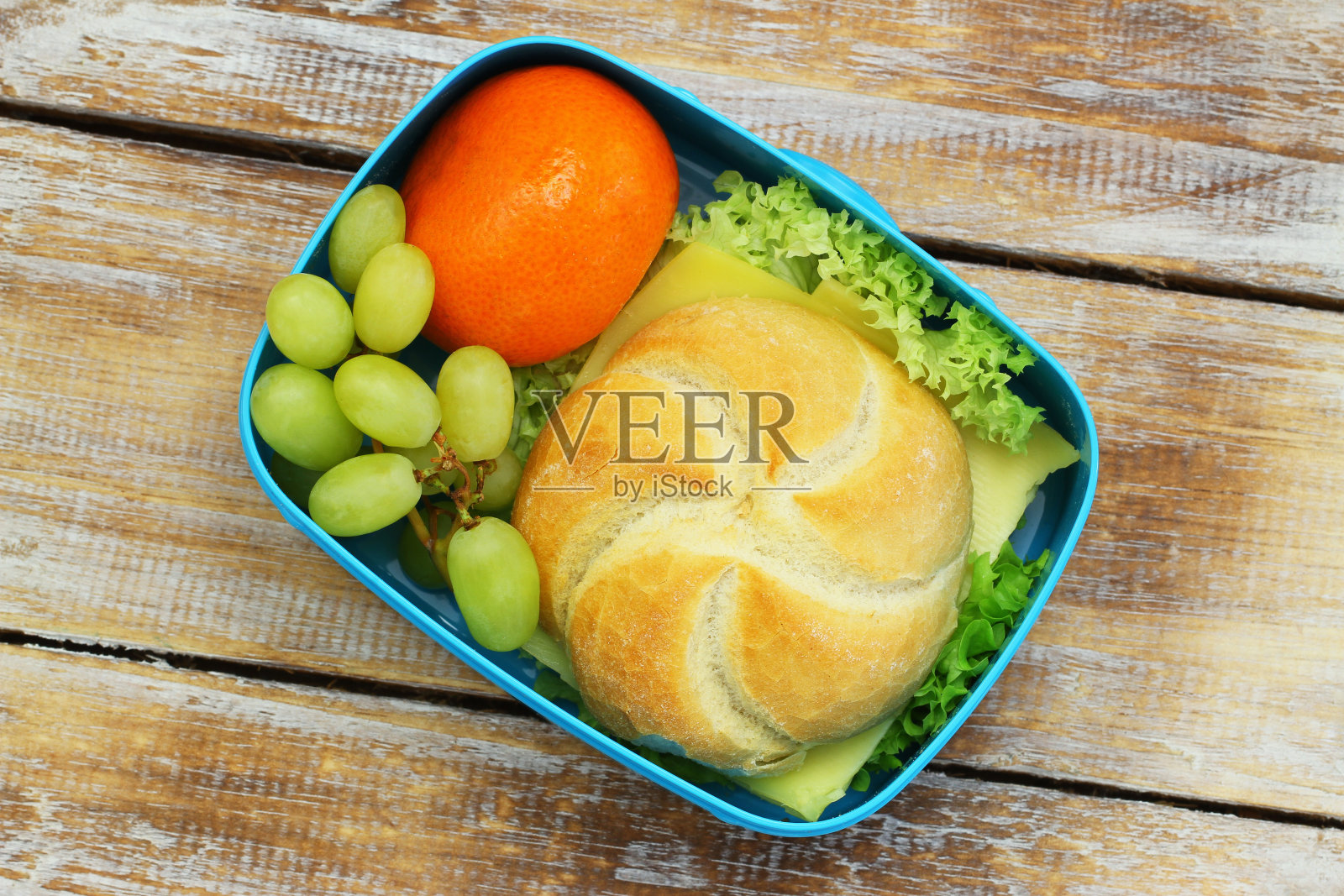 午餐盒，芝士卷，橘子和葡萄在乡村木质表面照片摄影图片