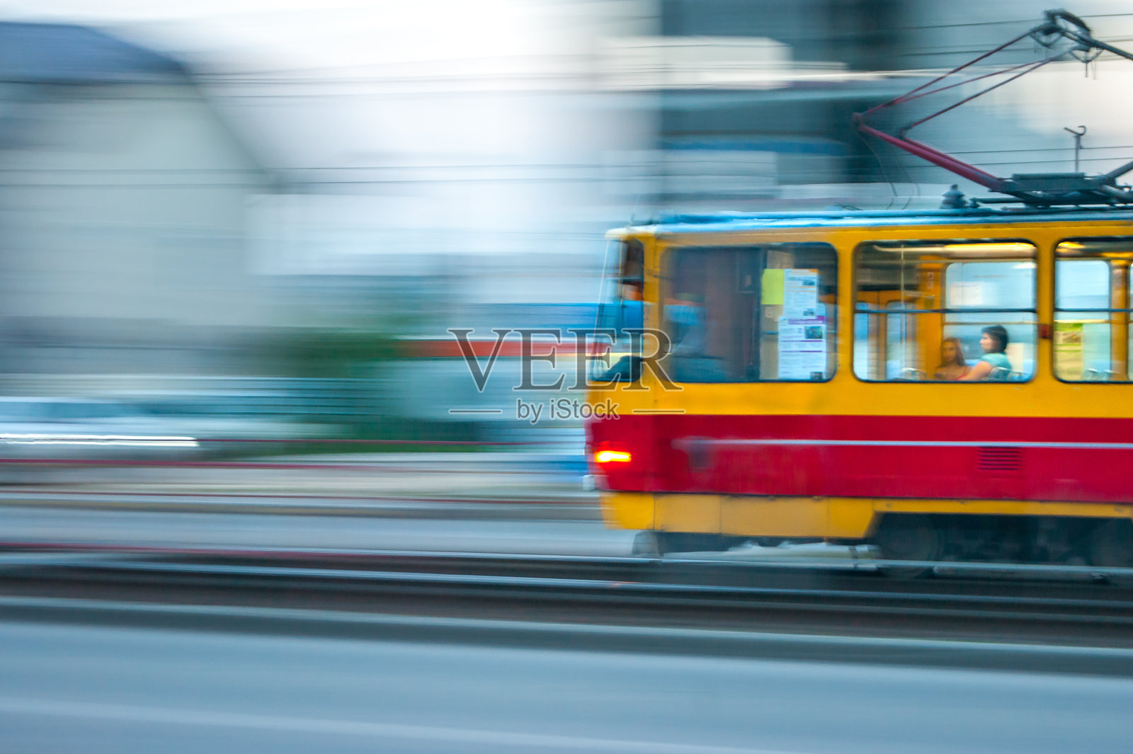 快速移动的红色和黄色有轨电车在城市与灯光，平移模糊效果照片摄影图片
