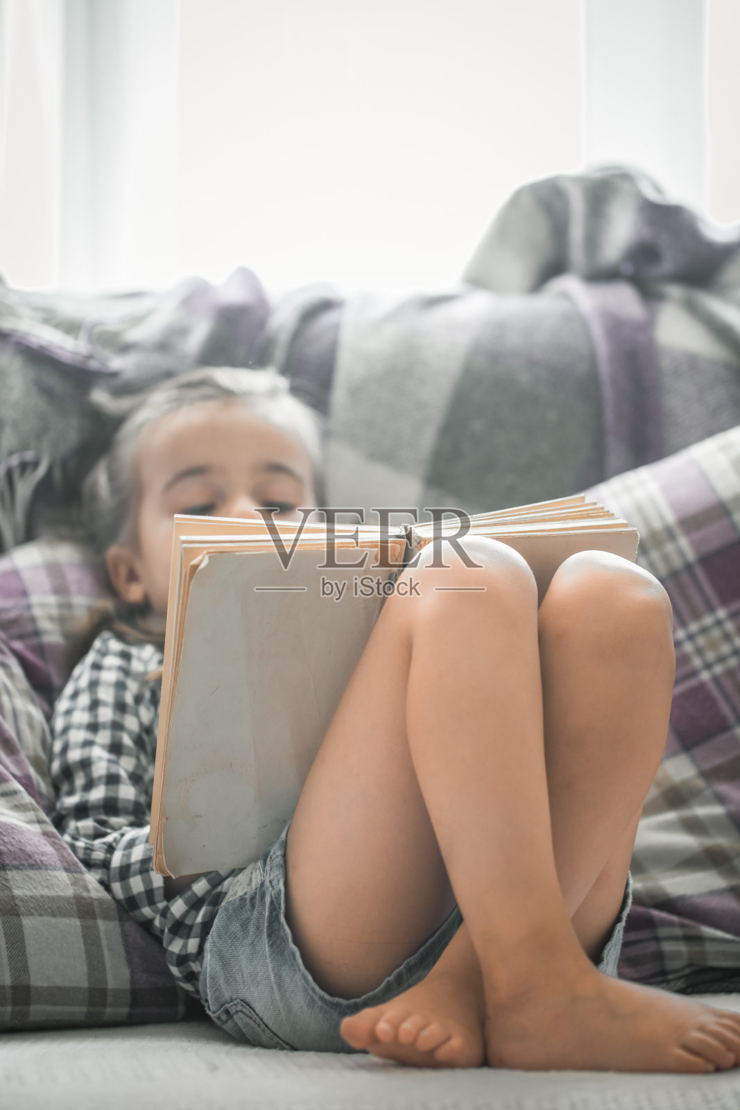 小女孩在沙发上看书照片摄影图片