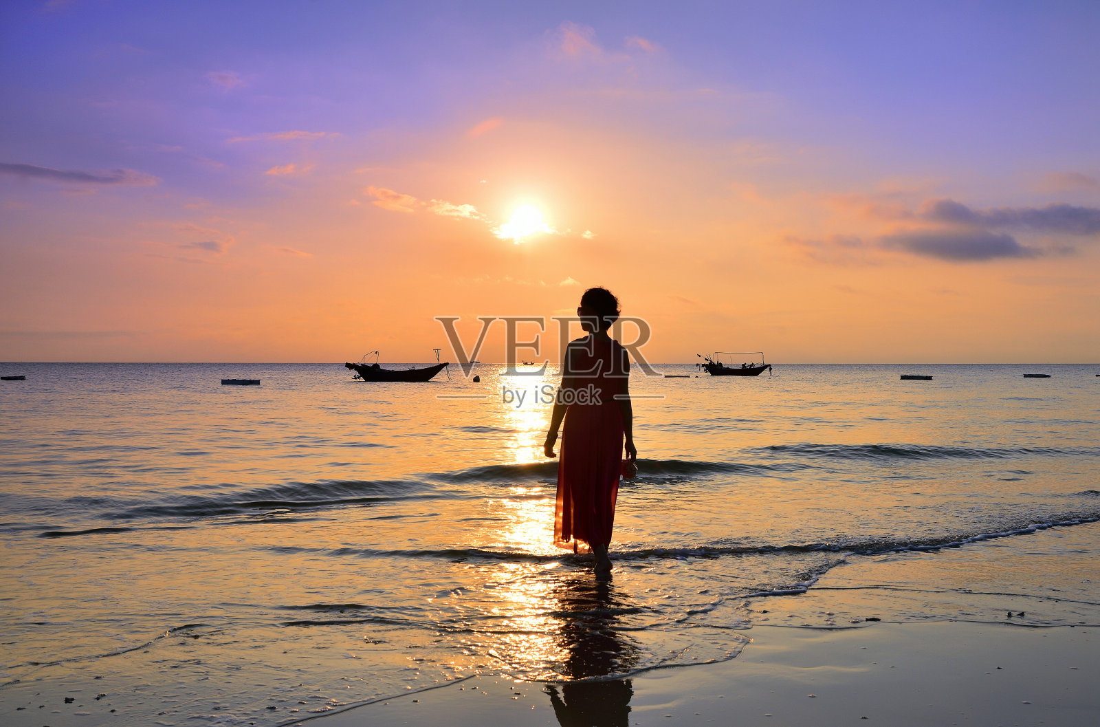 黄昏时分，一个女人站在海边，轮廓分明照片摄影图片