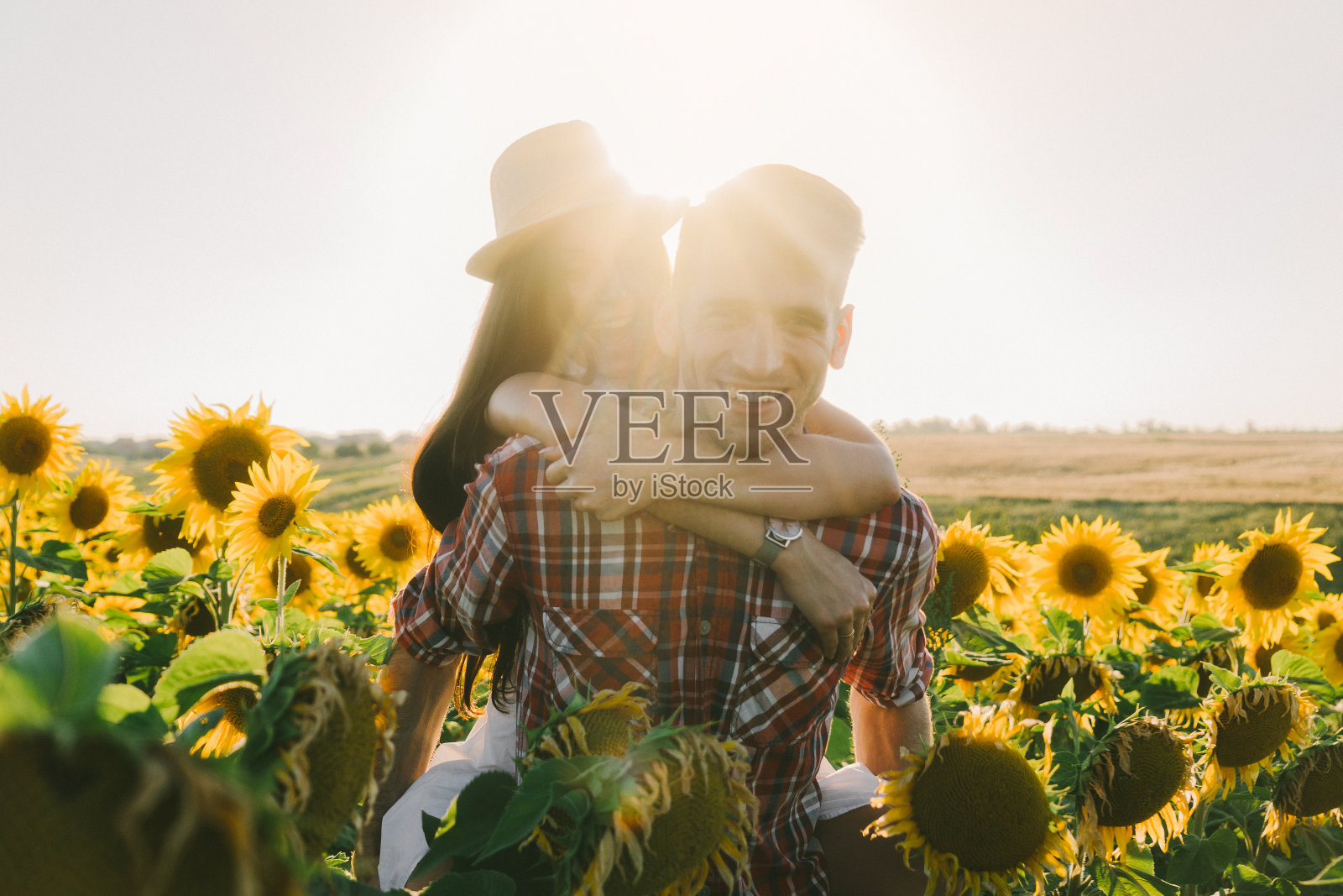 一对情侣在夕阳下的向日葵地里拥抱照片摄影图片