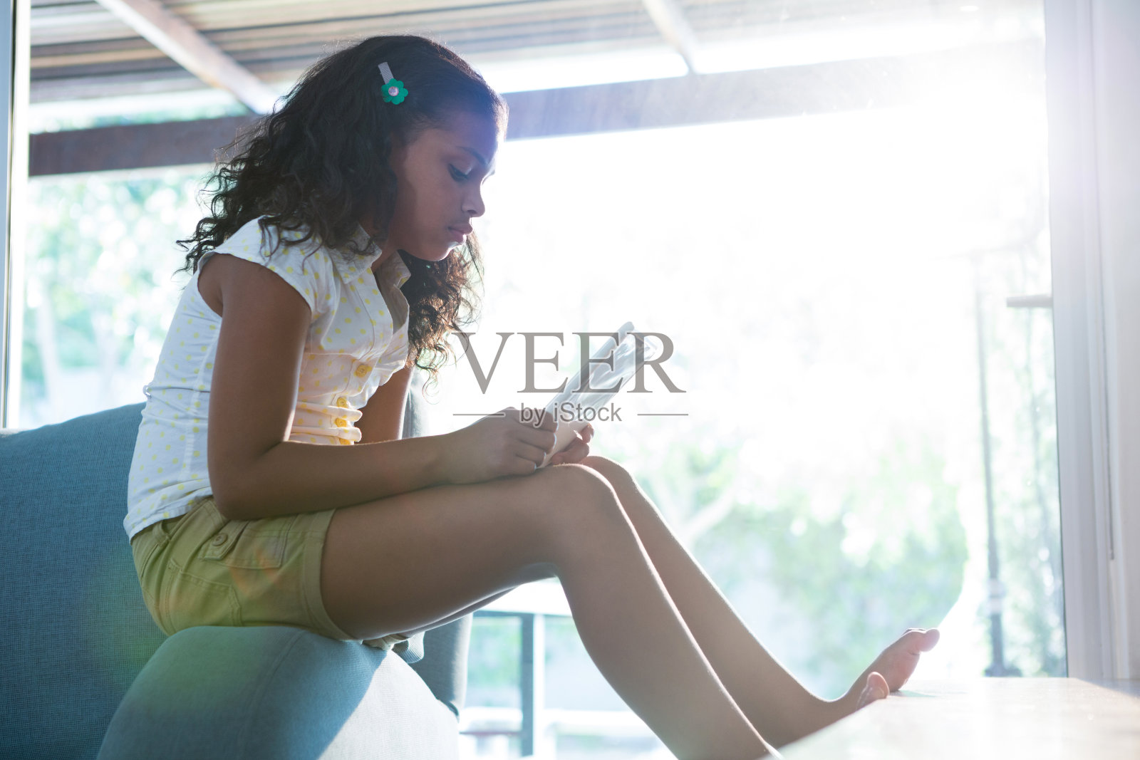 女孩坐在扶手椅上使用平板电脑的侧视图照片摄影图片