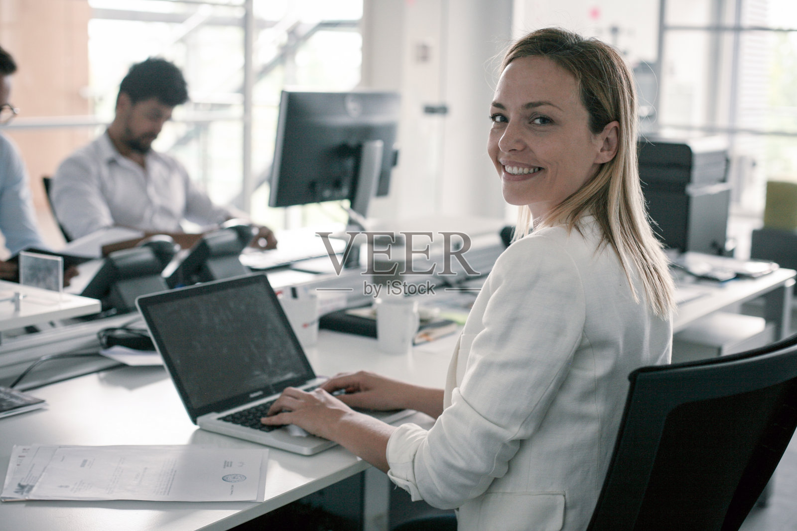 职场女性。女人一边用笔记本电脑一边看摄像头。照片摄影图片