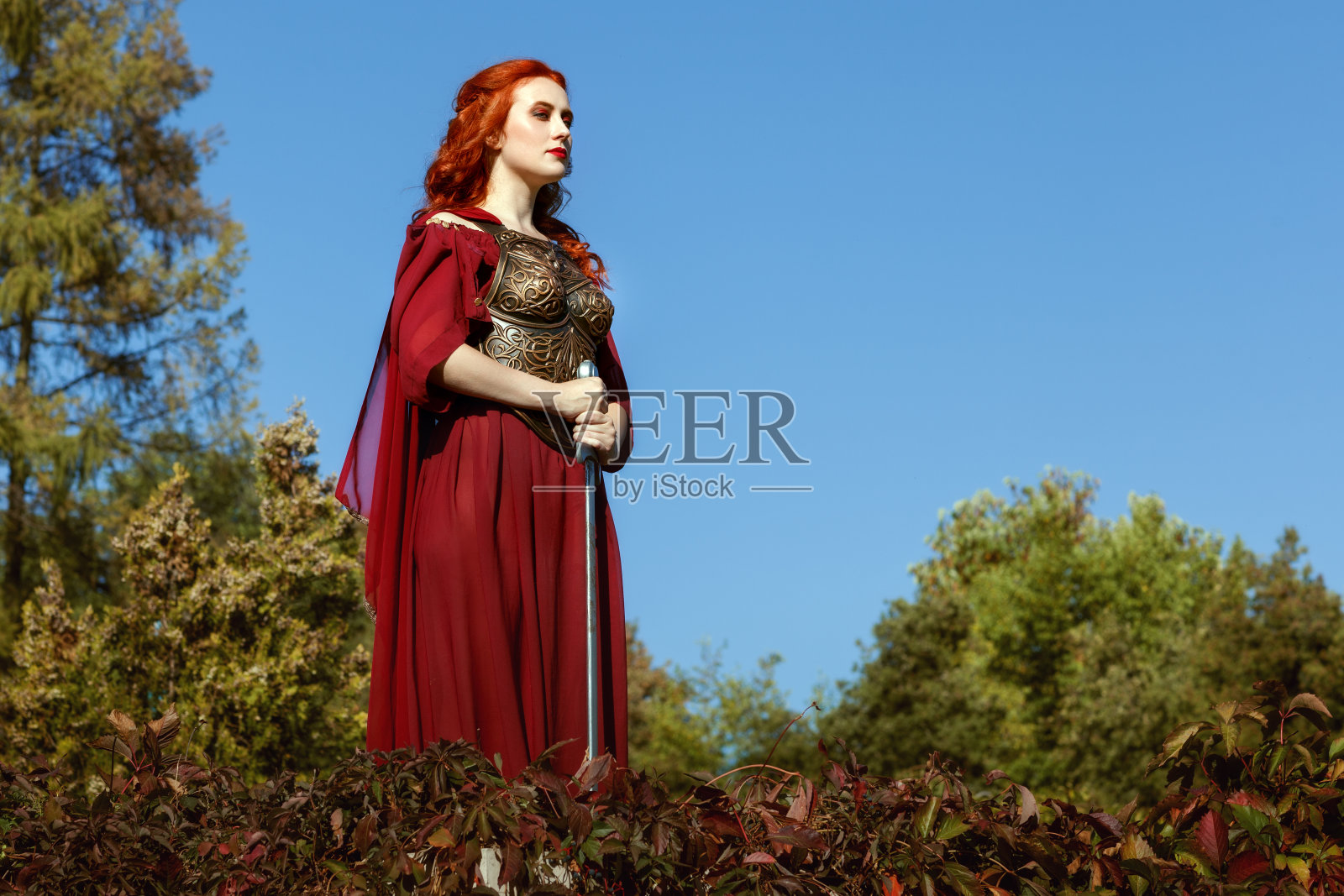 女人高高站着，手里拿着剑。照片摄影图片