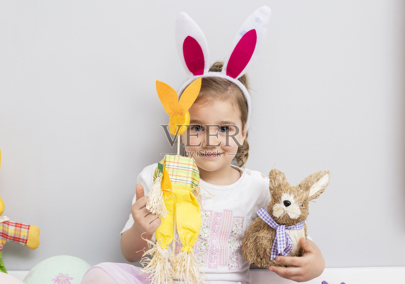 漂亮的小女孩在玩复活节彩蛋和兔子娃娃照片摄影图片