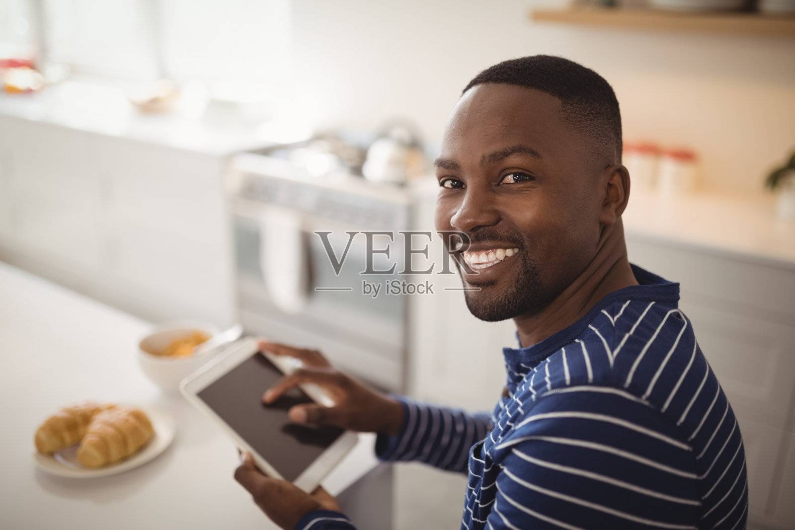 微笑的男人在厨房使用数码平板电脑照片摄影图片