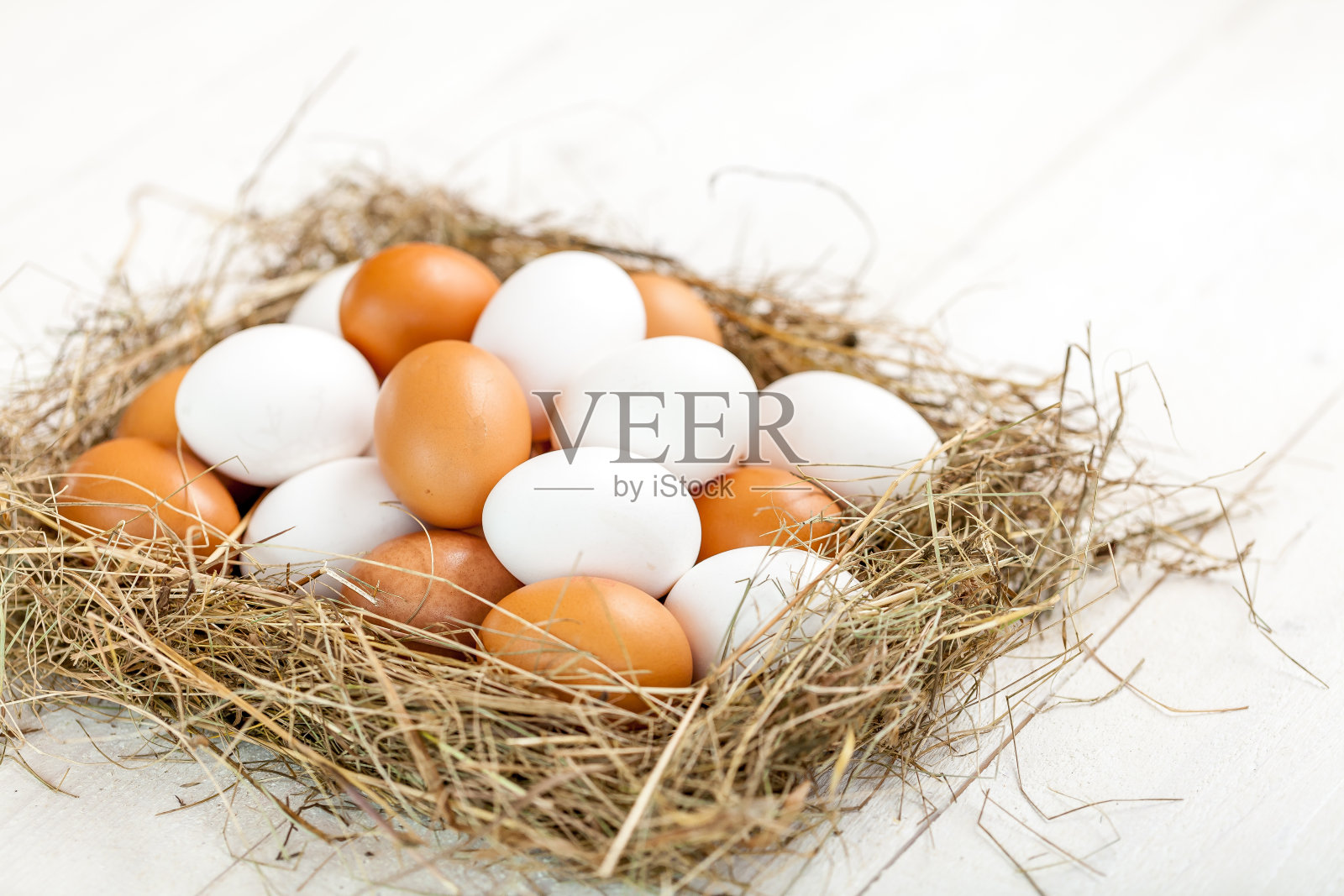 新鲜的乡村鸡蛋和稻草在质朴的木制白色桌子上照片摄影图片