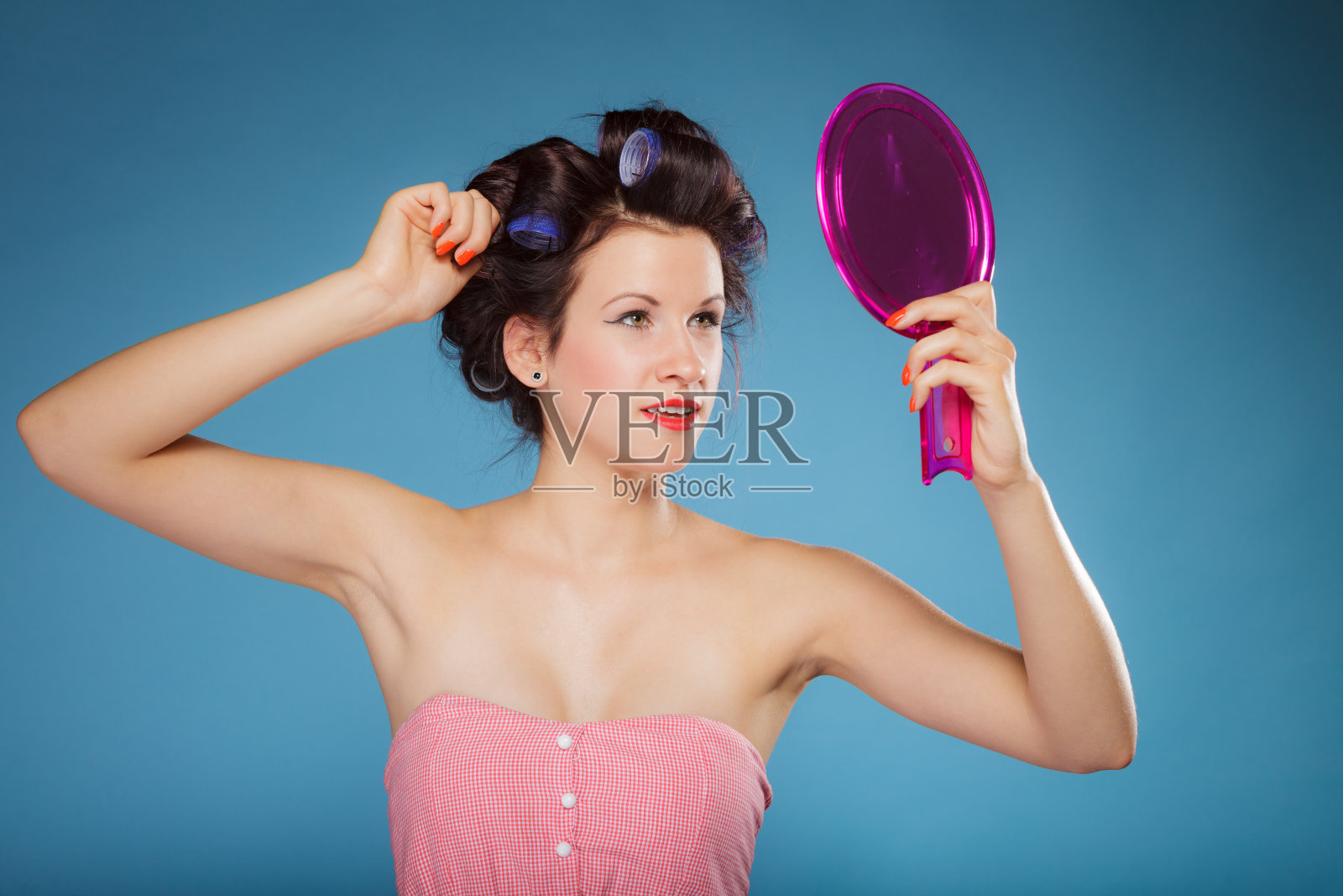 用卷发器做造型的女孩看着镜子照片摄影图片