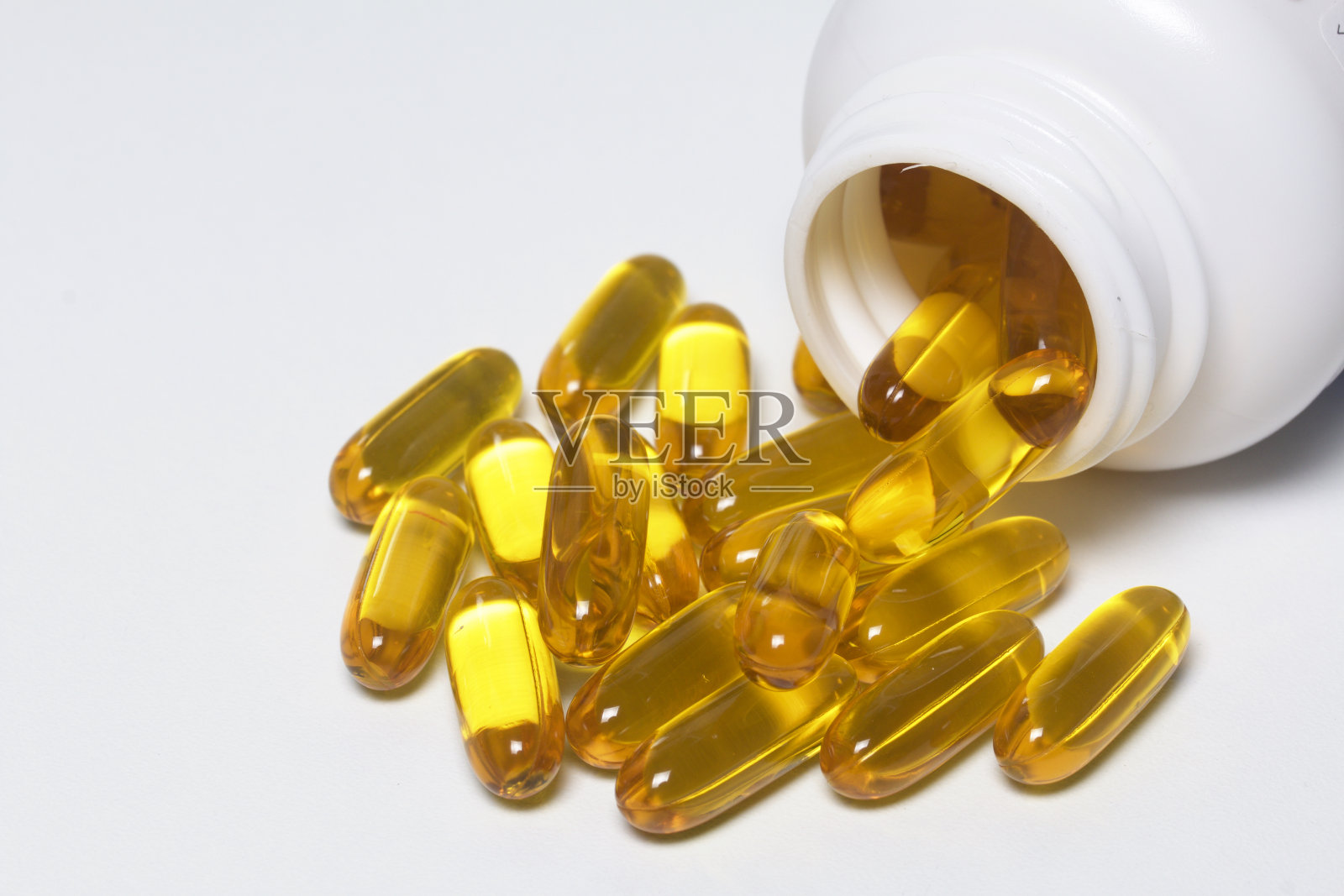 黄色的药丸从塑料瓶倒在白色的表面上。从以上观点。照片摄影图片