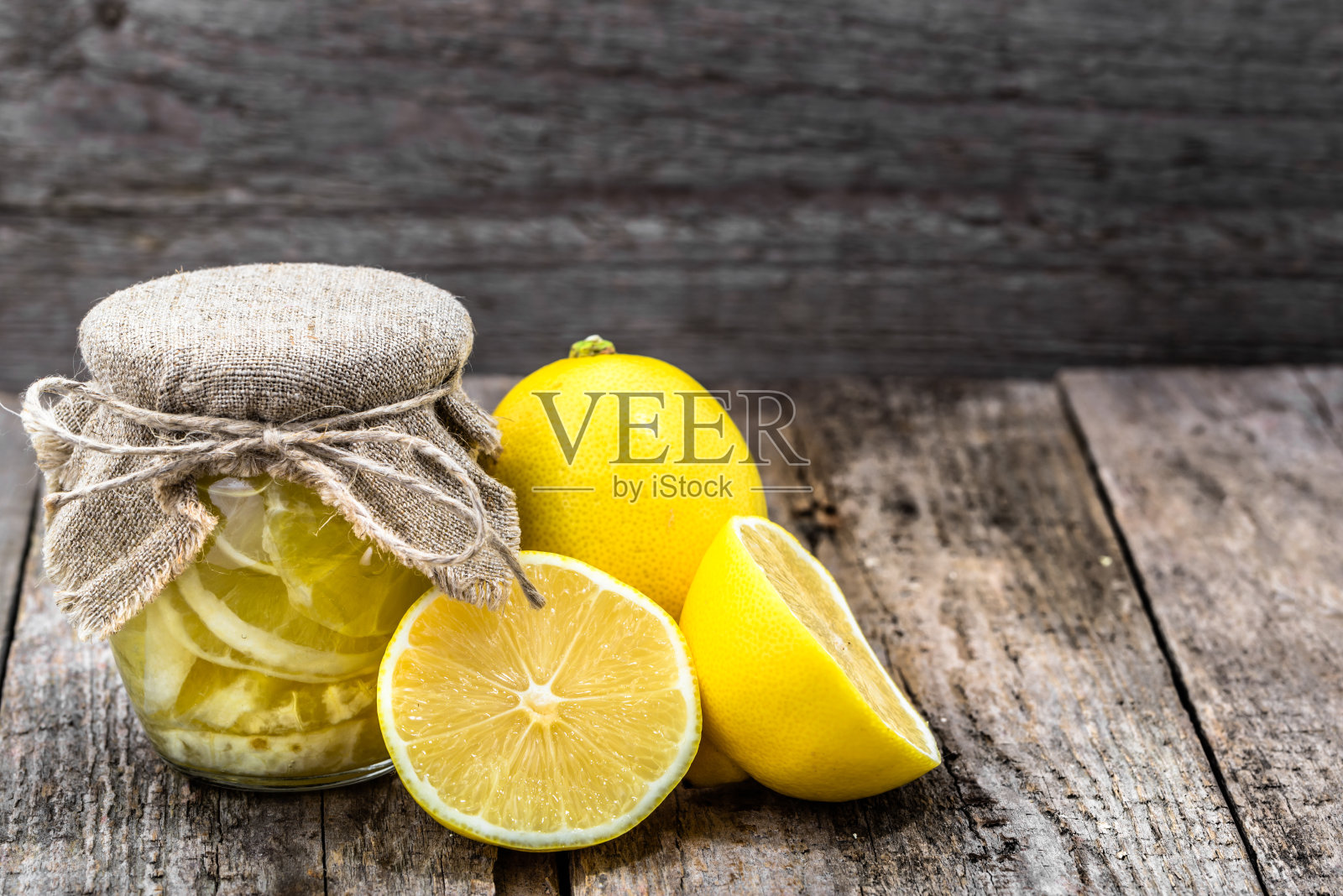 新鲜柠檬片和糖在一个玻璃罐在木制背景。为冬天自制保存食物。照片摄影图片