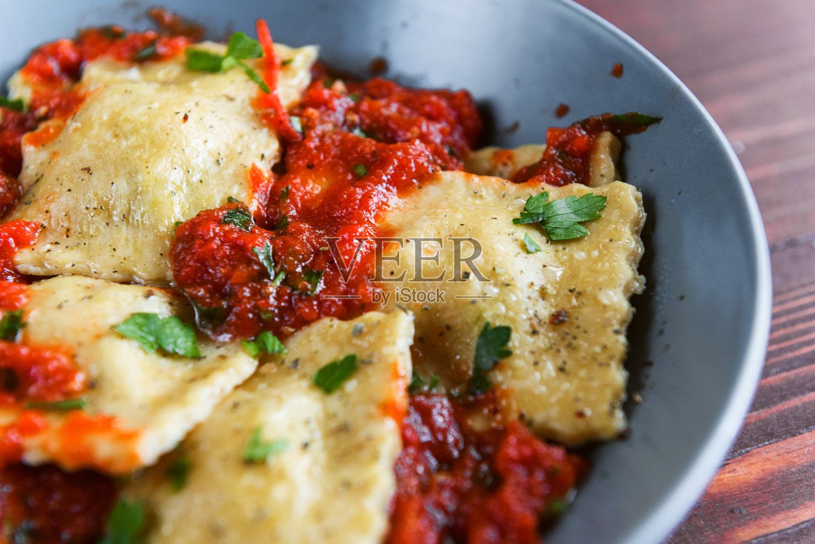 美味的蕃茄酱意式馄饨在一个盘子，在一个木制的背景照片摄影图片