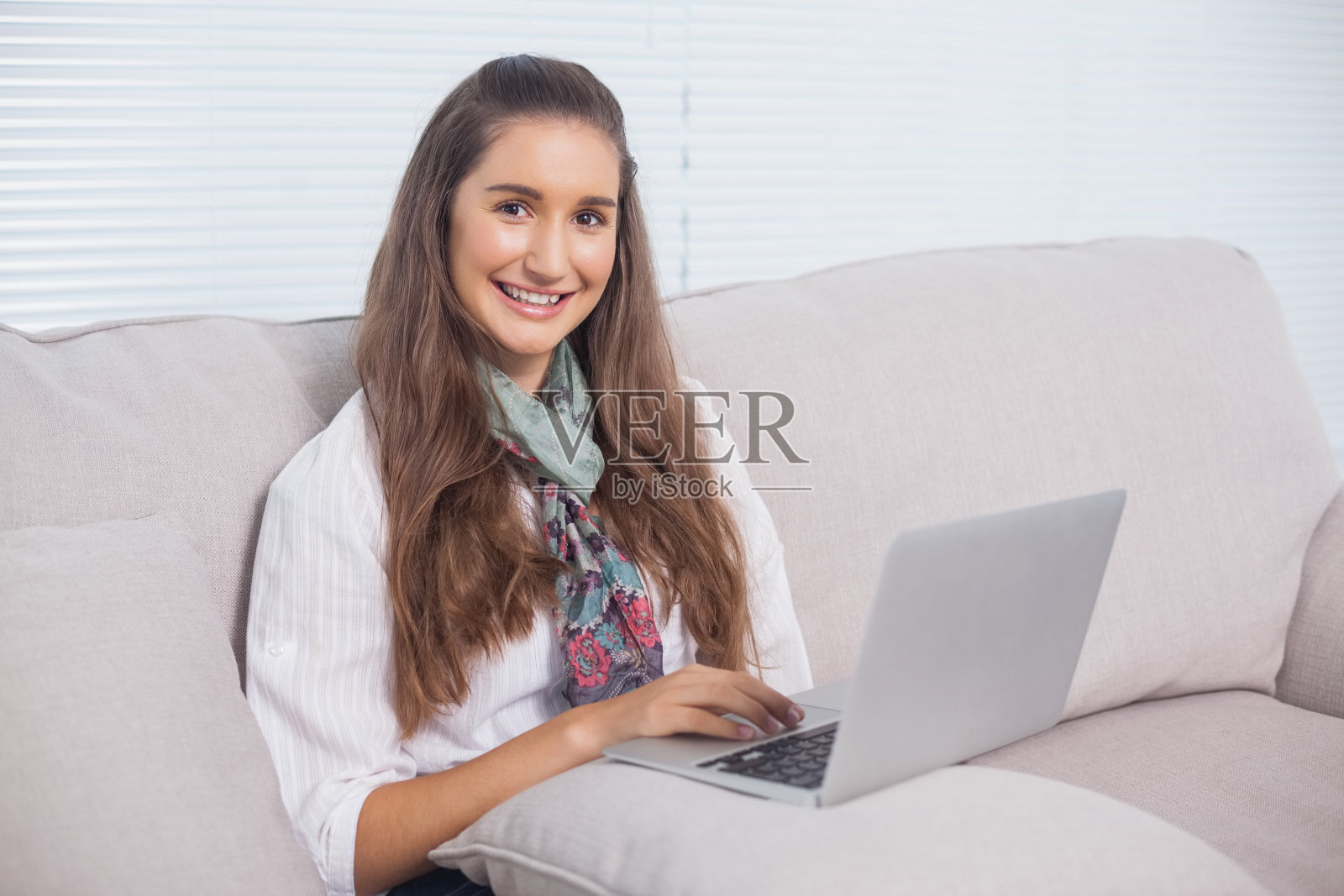 欢快华丽的模特坐在沙发上使用笔记本电脑照片摄影图片