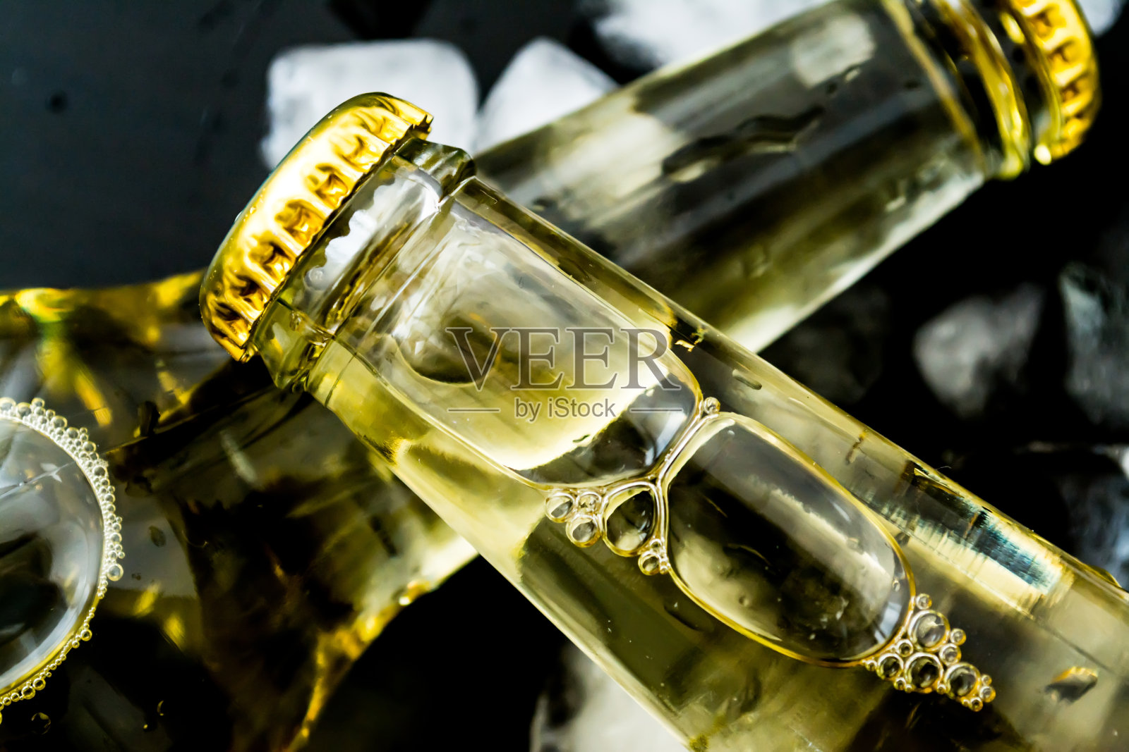 啤酒在瓶子与气泡在冰块近距离在一个黑暗的背景照片摄影图片